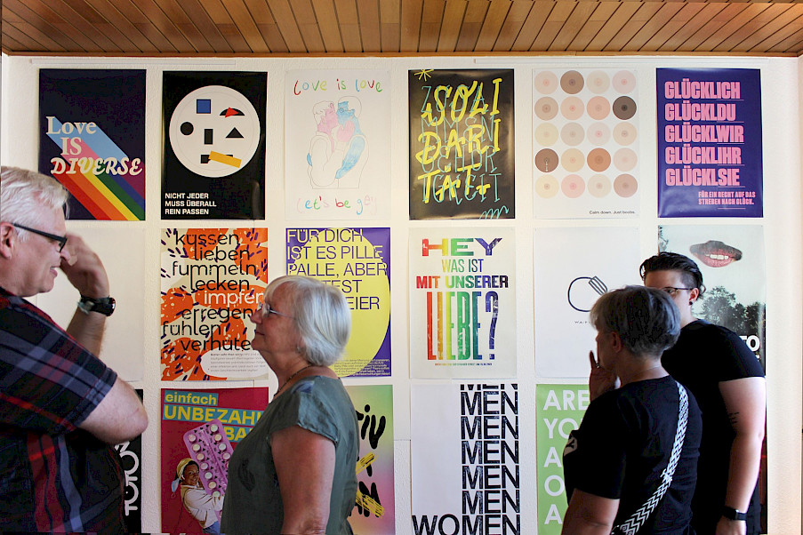 Einige Gäste im Gespräch vor der großen Plakatwand im zweiten Ausstellungsraum